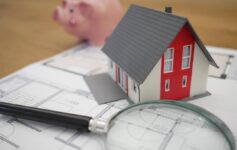white and red wooden house beside a grey-framed magnifying glass