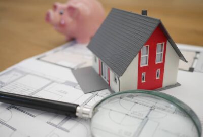 white and red wooden house beside a grey-framed magnifying glass