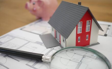 white and red wooden house beside a grey-framed magnifying glass